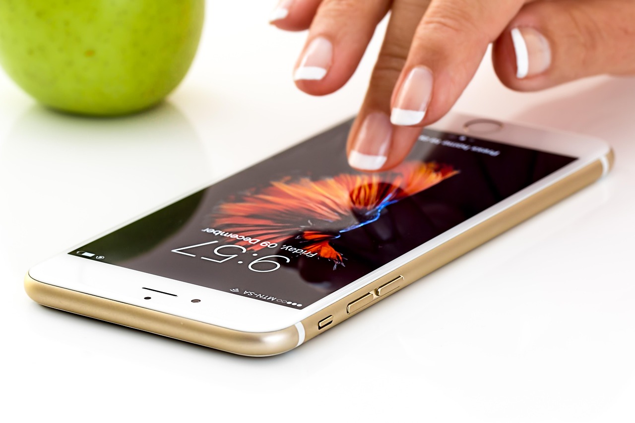 Close-up of a hand using a gold smartphone on a table